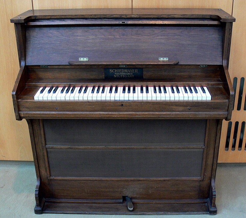 Fotografia: ciemny drewniany instrument przypominający małe pianino z klawiaturą